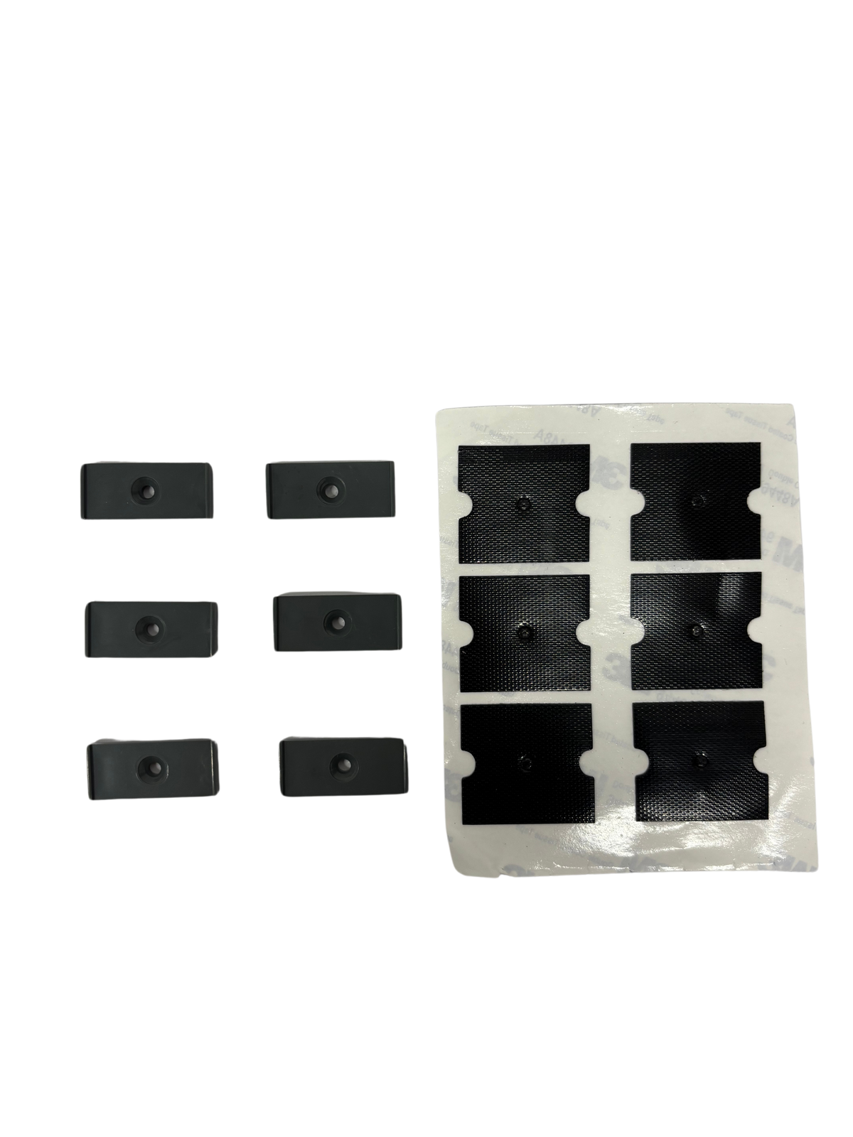 Six small black rectangular cleaning tool accessories next to a sheet of six adhesive black patches on a white backing.