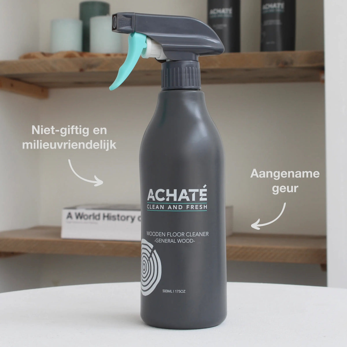 Black spray bottle labeled Achaté wooden floor cleaner with trigger nozzle, placed on a white surface in a home setting with wooden shelves in the background.