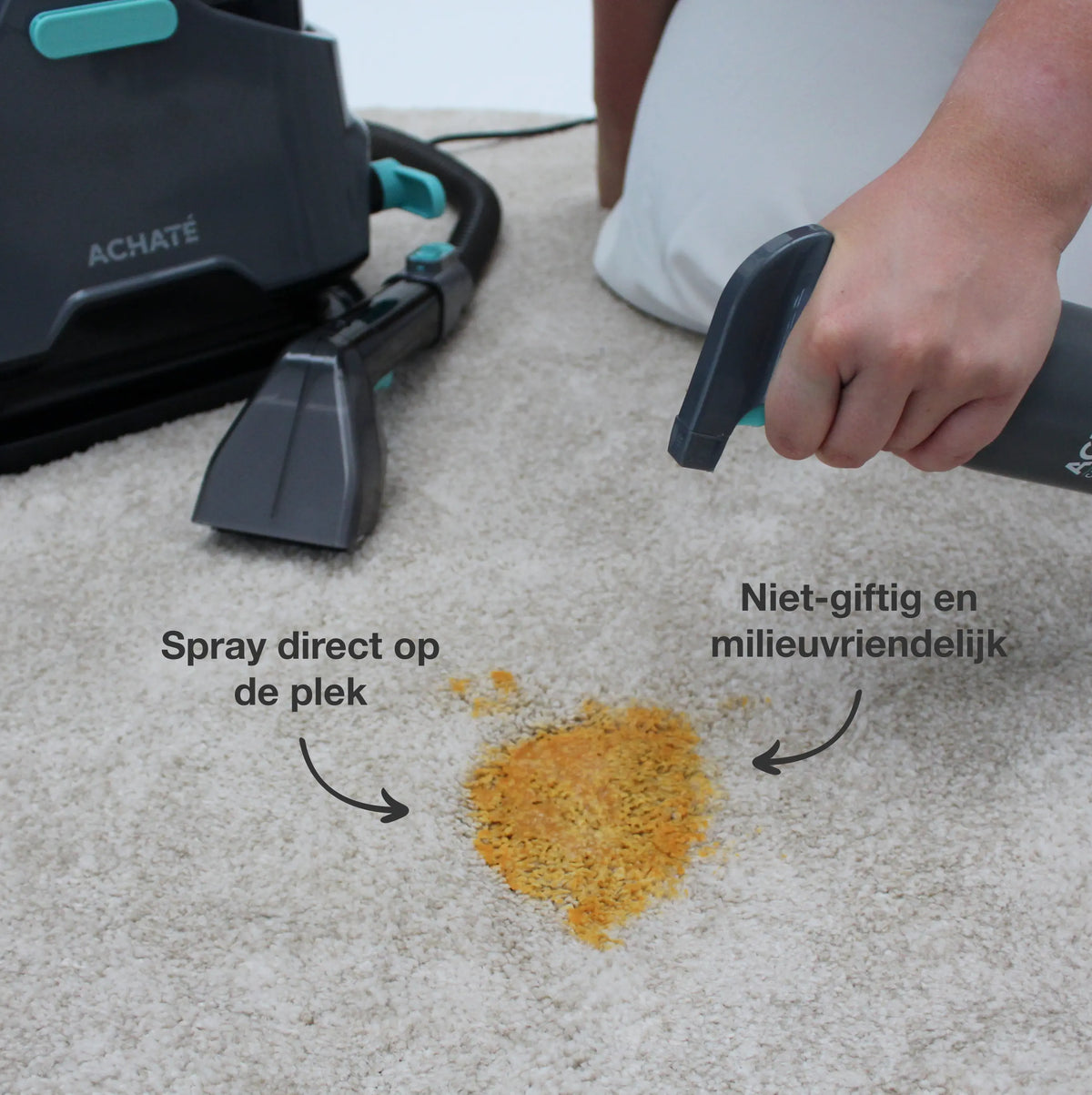 Person using a handheld steam cleaner with a spray nozzle to treat a stain on light-colored carpet near a black and teal cleaning device.