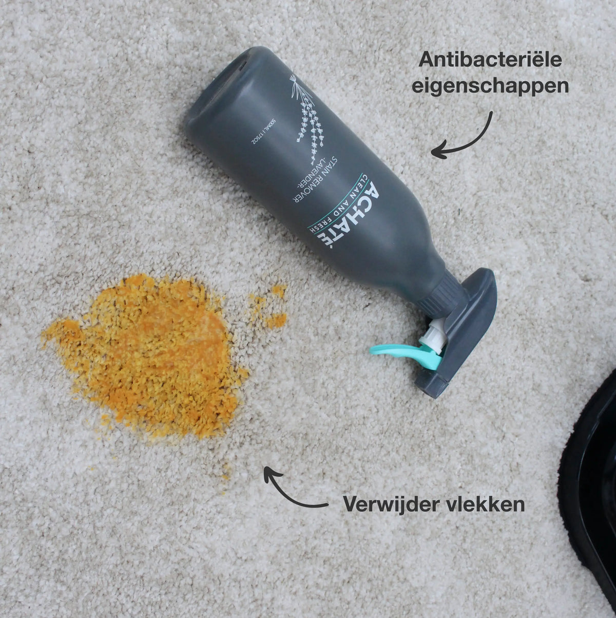 Dark gray spray bottle lying on beige carpet next to a yellow stain, highlighting antibacterial properties and stain removal effectiveness