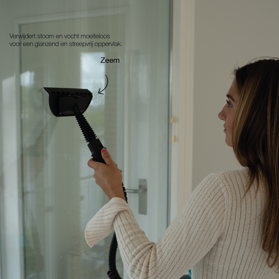 Woman using a handheld steam cleaner with a scraper attachment to clean a glass door, removing steam and moisture for a streak-free finish.