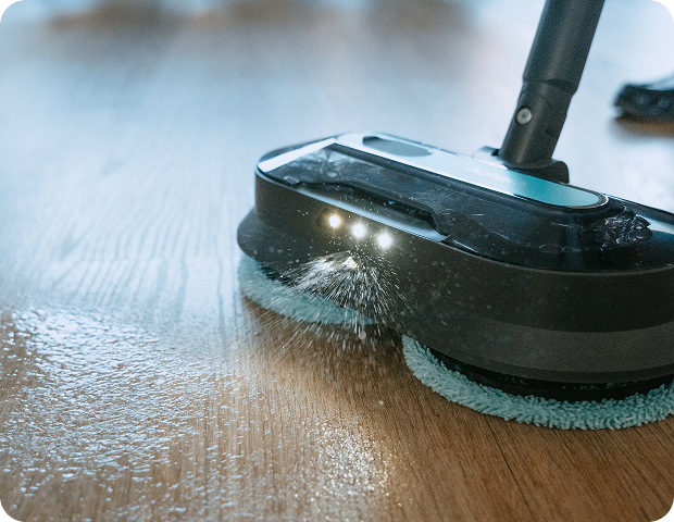 Close-up of a cordless steam cleaner with LED lights operating on a wooden floor, demonstrating chemical-free deep cleaning with high steam pressure.