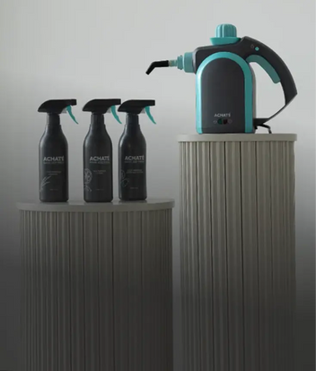 Three Achaté spray cleaners and a teal handheld steam cleaner displayed on ribbed pedestals.