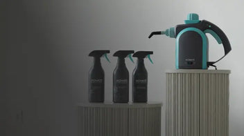 Three Achaté spray cleaners and a teal handheld steam cleaner displayed on ribbed pedestals.