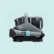 Compact, modern cleaning device with a sleek design in gray and black, featuring a handle and control buttons, set against a light blue background.