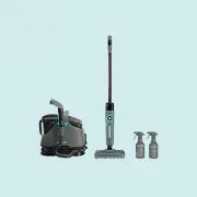 Lightweight cordless stick vacuum cleaner with high steam pressure, accompanied by two spray bottles and a separate cleaning base unit.