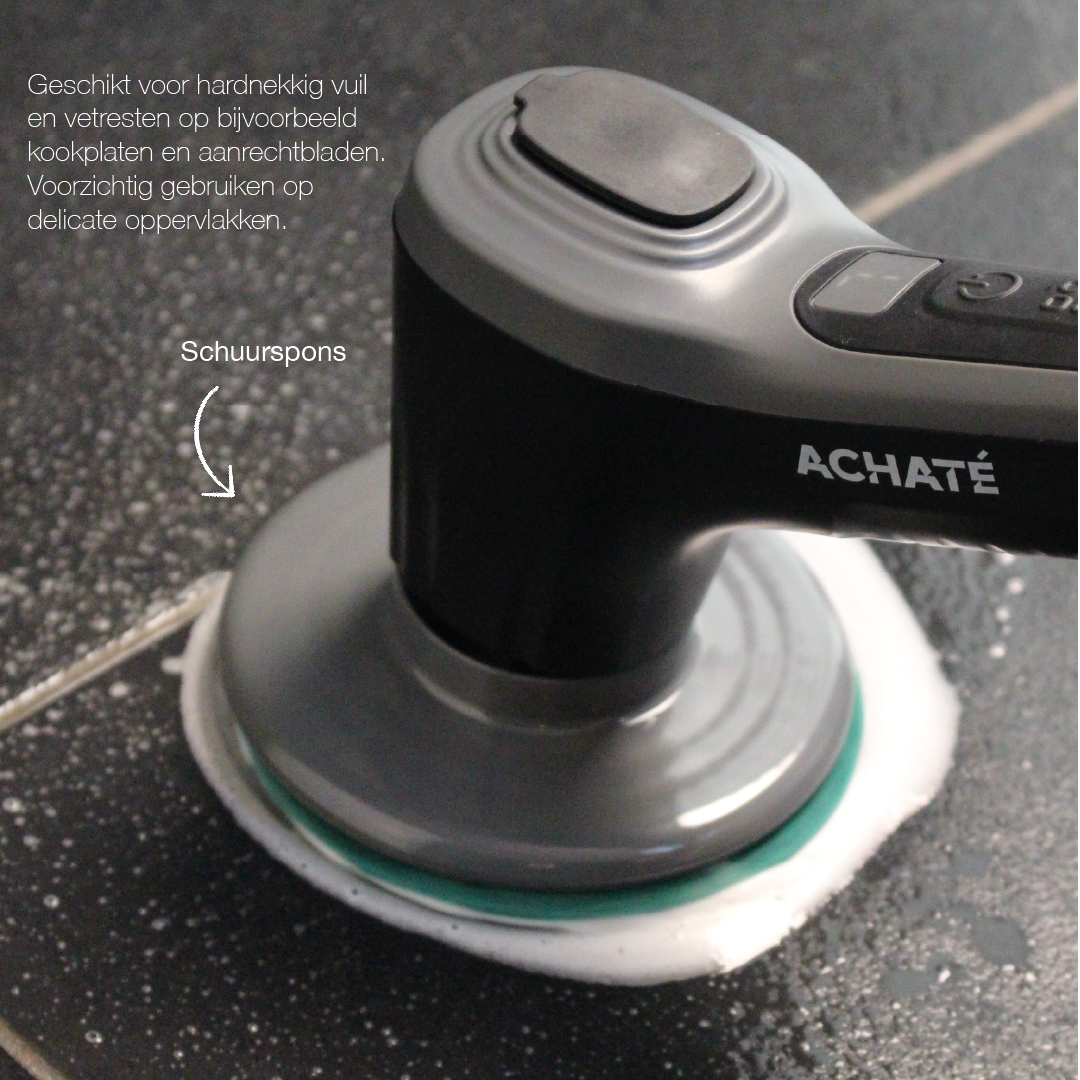 Close-up of a black handheld cleaning brush with a round abrasive scrubbing pad applying foam to a dark textured surface, featuring the brand name Achaté.