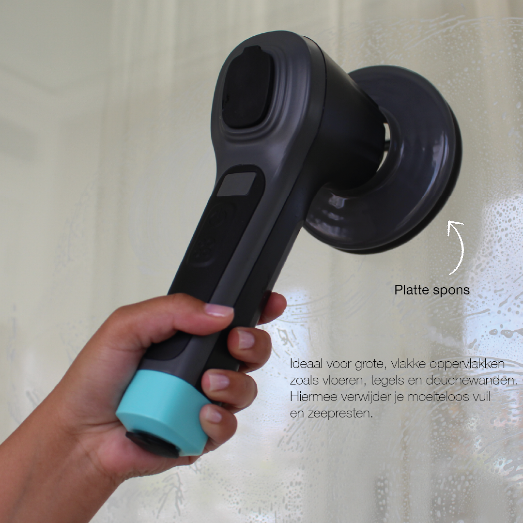 Handheld cordless electric cleaning brush with a flat sponge attachment scrubbing a glass surface with visible soap suds.